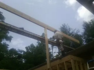 Carpenter setting a ridge beam over a new addition frame — Ice Dam Removal by Roofing Brothers in Jarratt