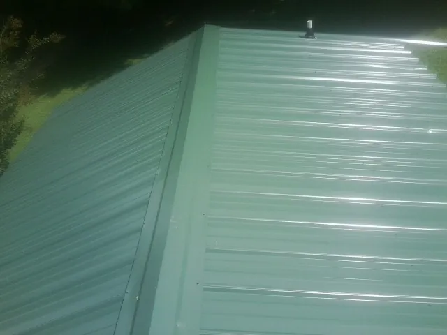 New green metal panels meeting at the ridge of a roof — Flat Roof Repair work by our crew in Jarratt