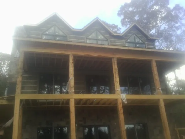 Dormers and porch framing on a large log home under construction — Roof Coating work by our crew in Jarratt