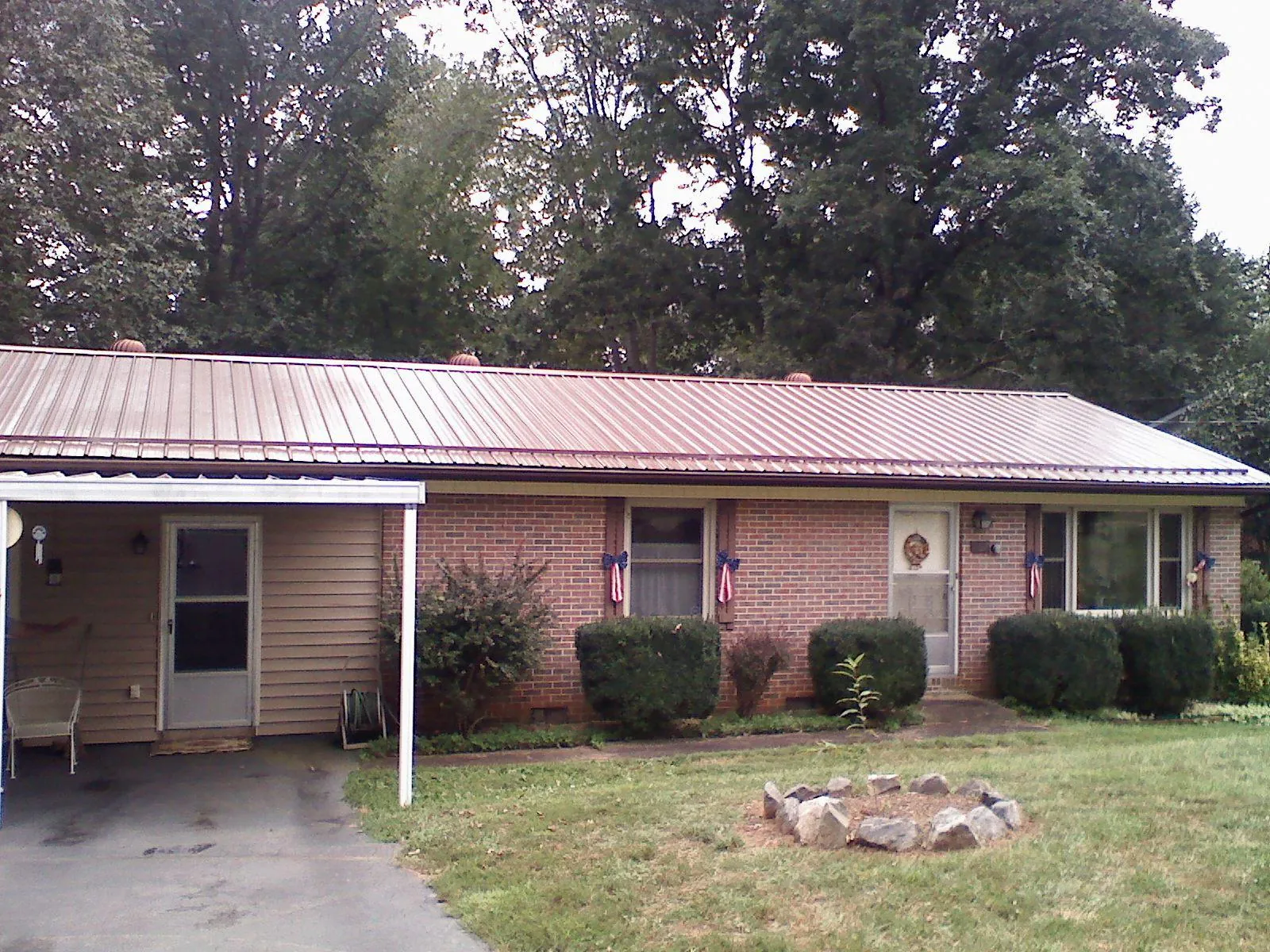 Bronze metal roof and carport on a brick ranch home — Roof Repair work by our crew in Jarratt