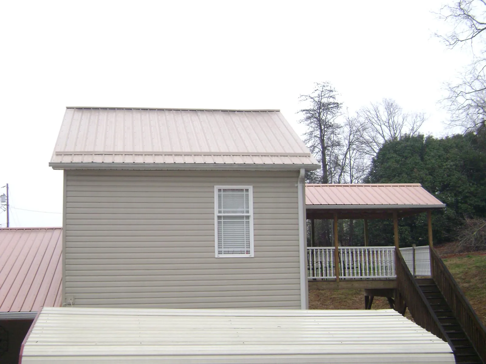 Tan metal roofs on a two story addition and attached porch, from a Roof Replacement job in Jarratt