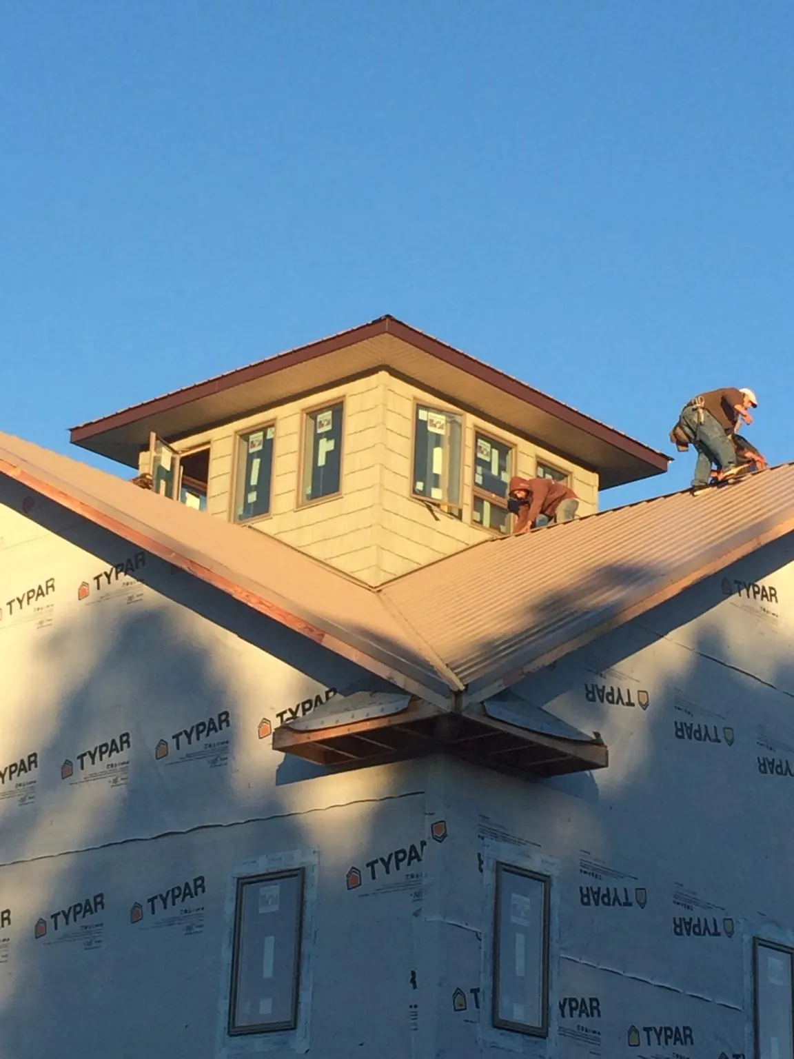 Roofers working around a rooftop cupola on a new metal roof at sunset — Roof Waterproofing in Jarratt by Roofing Brothers